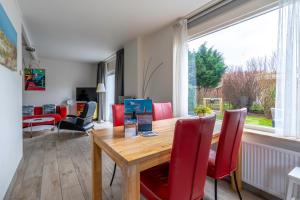 a dining room with a wooden table and red chairs at Californiëweg 9A in De Koog