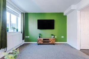 sala de estar con TV en una pared verde en Modern 3 BR Olive Suite - Sleeps 7 en Clock Face