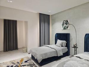 - une chambre avec un lit à tête bleue dans l'établissement حي الامواج العزيزية, à Raʼs Munaysif