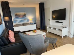 sala de estar con cama, sofá y TV en Ostseeliebe M-5-6, en Heiligenhafen