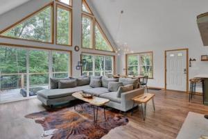 ein Wohnzimmer mit einem Sofa, Tischen und Fenstern in der Unterkunft Evergreen Escape - Jim Thorpe Multi Ski Resort in Albrightsville