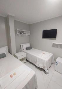 a room with two beds and a flat screen tv at Pousada Chapada do Araripe in Araripina