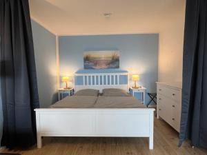 1 dormitorio con 1 cama blanca y 2 mesitas de noche en Ostseeliebe M-5-6, en Heiligenhafen