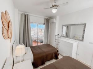 a white bedroom with a bed and a window at Club Maritimo at Ronda III in Fuengirola