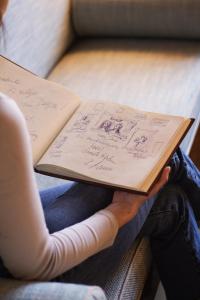a woman is holding a book with drawings on it at Schlossberghotel in Graz