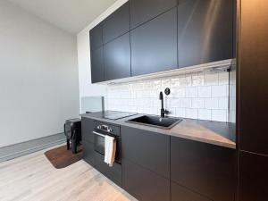 a kitchen with black cabinets and a sink at A charming little cottage in beautiful Hunnebostrand in Hunnebostrand