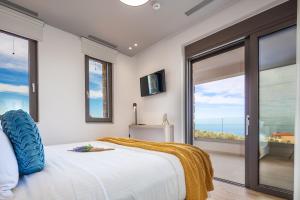a bedroom with a large bed and a large window at Oinolithos Luxury Villas in Kalamaki