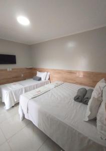 two beds in a hotel room with white sheets at Pousada Chapada do Araripe in Araripina