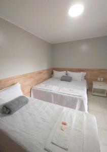 a bedroom with two beds with white sheets at Pousada Chapada do Araripe in Araripina