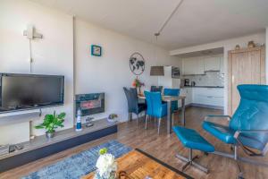 un salon avec une télévision et des chaises bleues dans l'établissement Appartementencomplex Juliana 126, à De Koog 4 autres photos