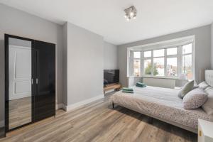 a bedroom with a bed and a large window at Edgware Oasis: Modern Haven near Tube & Park in Edgware