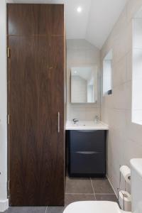 a bathroom with a sink and a wooden door at Edgware Oasis: Modern Haven near Tube & Park in Edgware