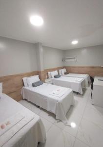 a room with three beds with white sheets at Pousada Chapada do Araripe in Araripina