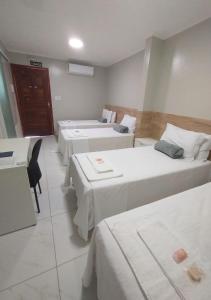 a hotel room with three beds and a table and chairs at Pousada Chapada do Araripe in Araripina