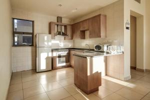 a kitchen with wooden cabinets and a white refrigerator at Family Sweet - Apartment in Tala Bay Aqaba in Al Burj