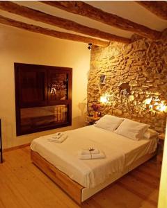 a bedroom with a large bed in a stone wall at Cal Cintet in Vilanova de Meyá