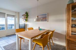 a dining room with a wooden table and yellow chairs at Appartementencomplex Juliana 142 in De Koog