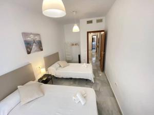 a hotel room with two beds and a hallway at Apartamento en centro con garaje in Sanlúcar de Barrameda