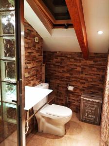 a bathroom with a toilet and a brick wall at Atico España in Las Rozas de Madrid