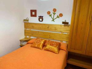 a bedroom with an orange bed with two pillows at Apartamento con jardín in Santander