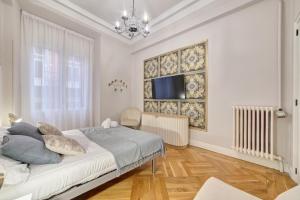 een witte slaapkamer met een bed en een televisie bij Apartamento Boutique centro Zapateria 45 in Pamplona