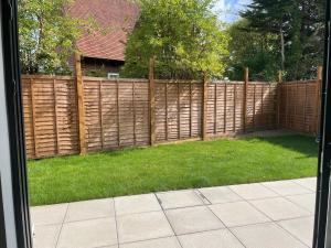 a backyard with a wooden fence and green grass at Modern Raynes Park Apartment x2 Bathroom*Garden*Wifi* in Raynes Park