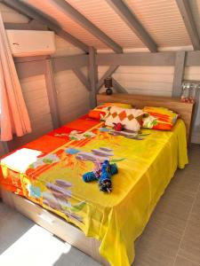 uma cama com um cobertor amarelo com brinquedos em 971C - "Ti Calebasse" an atypical cottage em Terre-de-Bas