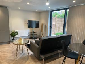 Modern Raynes Park Apartment x2 Bathroom*Garden*Wifi* في رينيس بارك: غرفة معيشة مع أريكة وطاولة