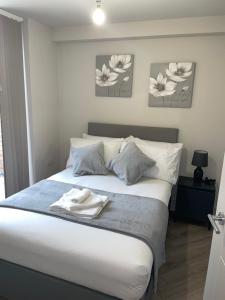 a bedroom with a white bed with three flowers on the wall at Modern Raynes Park Apartment x2 Bathroom*Garden*Wifi* in Raynes Park
