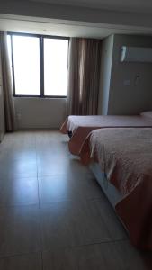 a hotel room with two beds and a window at Atlântico Flat in Natal +13 photos