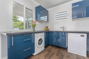 - une cuisine avec des placards bleus et un lave-linge/sèche-linge dans l'établissement 971H2 - Cottage "Marie-Galante" with private pool, à Malgré Tout