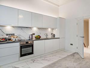 una cocina blanca con armarios y electrodomésticos blancos en 2 Bed in Carlisle 92868, en Carlisle