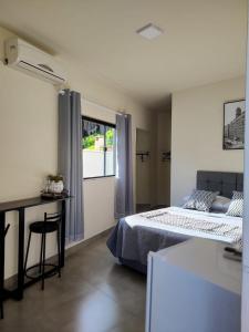 a bedroom with a bed and a desk and a window at Morada Stucchi in Balneário Camboriú