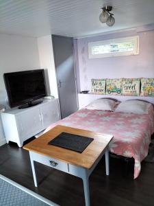a bedroom with a bed with a table and a tv at Studio très calme 5mn VICHY in Bellerive-sur-Allier