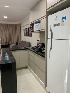 a kitchen with a white refrigerator in a room at Flat Mobiliado - Ap 43 L Hirondelle in Campinas