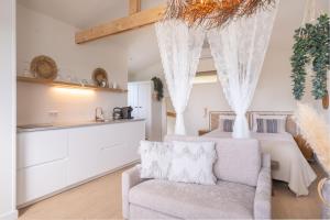 a bedroom with a bed and a chair and a couch at Yn 'e Haven Logies in Earnewâld