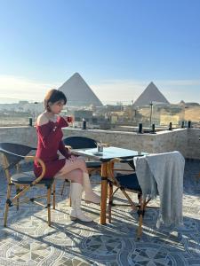 Tuya Pyramids View في القاهرة: امرأة تجلس على طاولة مع كوب