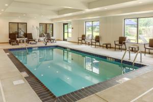 a pool in a hotel room with chairs and tables at Comfort Inn & Suites Amish Country in Gap