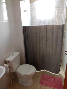 y baño con aseo y cortina de ducha. en Apartamento Super Aconchegante em Ambiente Familiar, en Contagem