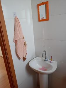 ein Badezimmer mit einem weißen Waschbecken und einem Spiegel in der Unterkunft Apartamento Super Aconchegante em Ambiente Familiar in Contagem