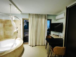 a bathroom with a tub and a desk and a television at Marina Beach Hotel in Tel Aviv