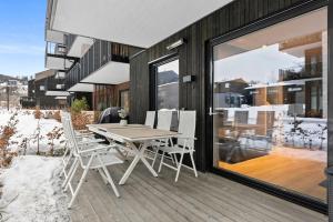 une terrasse en bois avec une table et des chaises dans un bâtiment dans l'établissement Moderne Leilighet med 2soverom Sentral beliggenhet, à Asker