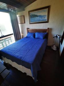 a bedroom with a bed with a blue comforter at Casa Azul na Praia do Verão Vermelho in Cabo Frio