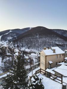 a snow covered city with a building and a mountain at “White Mountain”, Pisoderi in Pisoderi