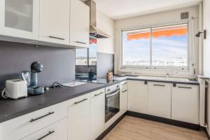 a kitchen with white cabinets and a large window at Appartement Leroy balcon - Welkeys in Clichy