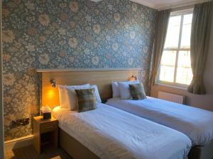 two beds in a hotel room with blue wallpaper at The Oxnoble in Manchester