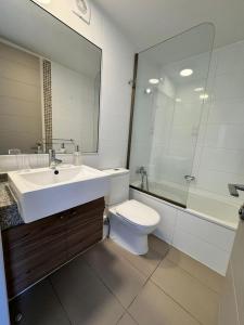 a bathroom with a sink and a toilet and a mirror at Lindo Departamento Amoblado en la Península Iquique in Iquique