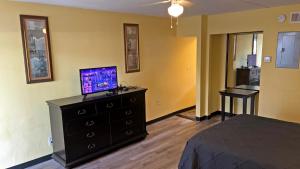 1 dormitorio con 1 cama y vestidor con TV en Avalon Resort of Deerfield Beach, en Deerfield Beach