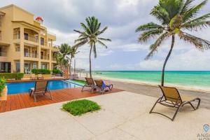 a resort with chairs and a pool and palm trees at Oceanfront Condo a Block Off 5th in Heart of Playa in Playa del Carmen