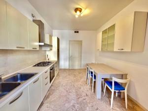 沃蓋拉的住宿－In Coorte di prestigio, nel pieno Centro di Voghera，厨房配有白色橱柜和木桌